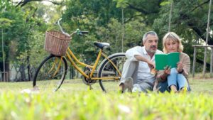 senior couple reading on grass