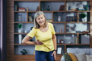 An older woman has severe pain in the abdomen after exercising at home