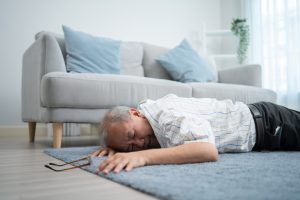Asian senior grandfather fainting and falling on the ground in the living room