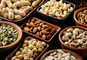 Assorted nuts and seeds in clay bowls on wooden kitchen table