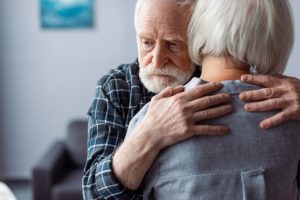 back view of senior woman hugged by husband, sick on dementia