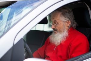 bearded senior man driving a car
