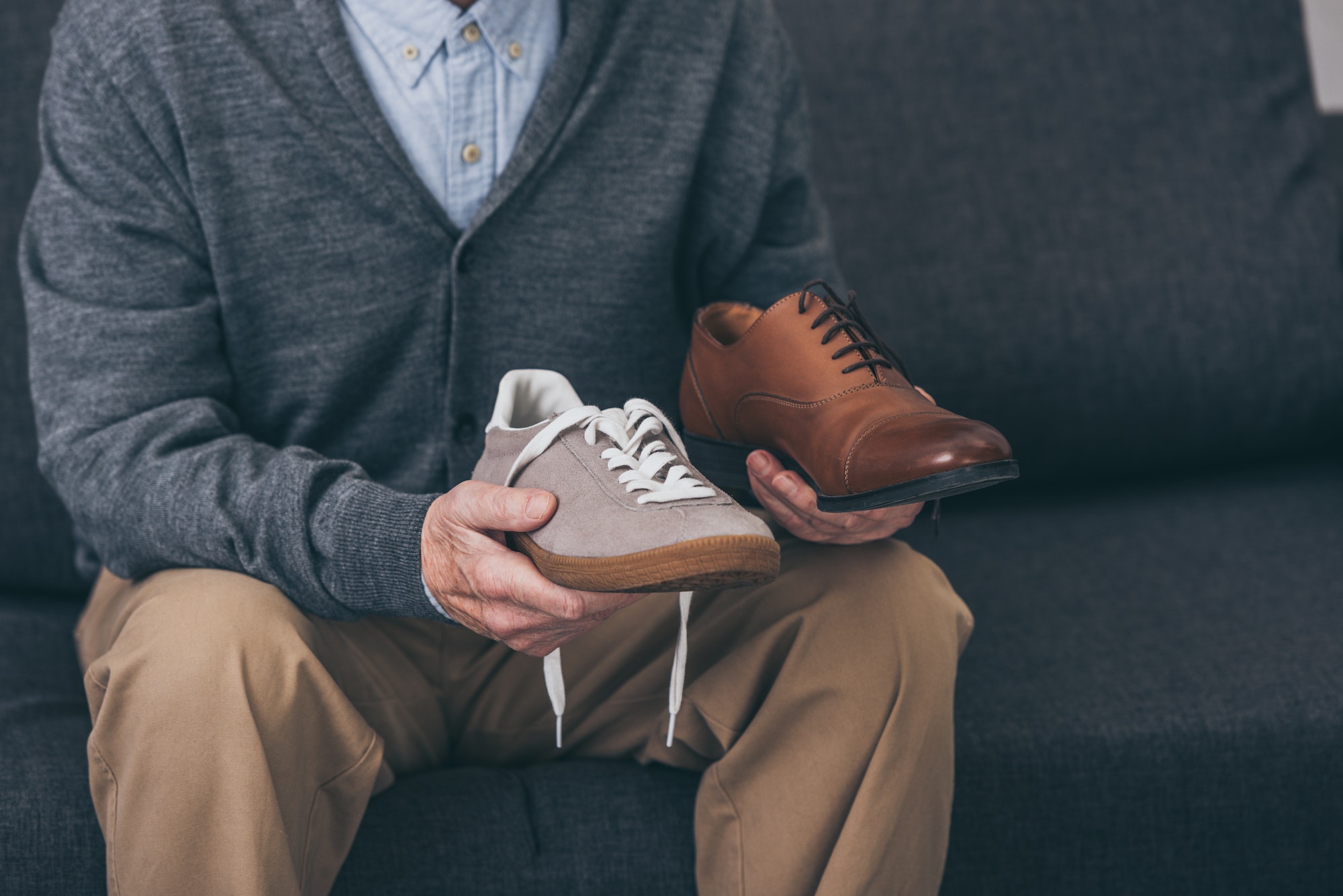 cropped view of senior man holding classic and modern shoes in hands