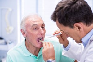 Doctor examining senior patients mouth