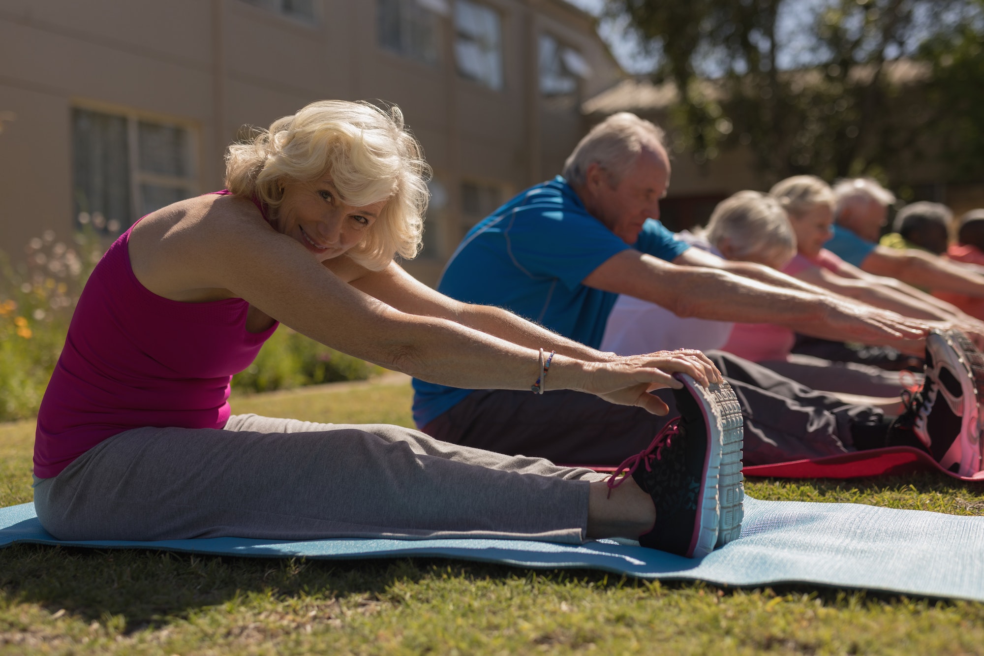 Group of senior people exercising in the park with senior woman looking at the camera