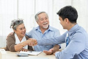 Happy senior couple handshaking with real estate agent
