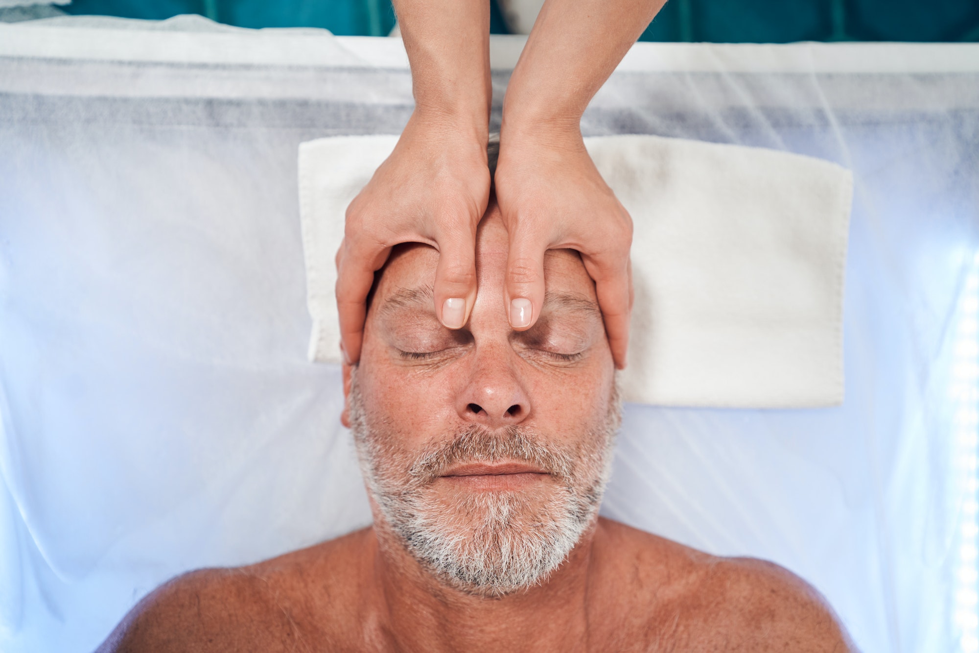 Man receiving professional scalp massage in spa salon