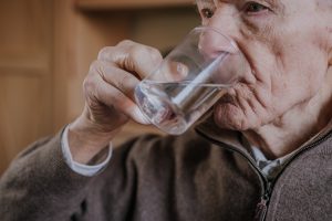 Old man drinking water closeup