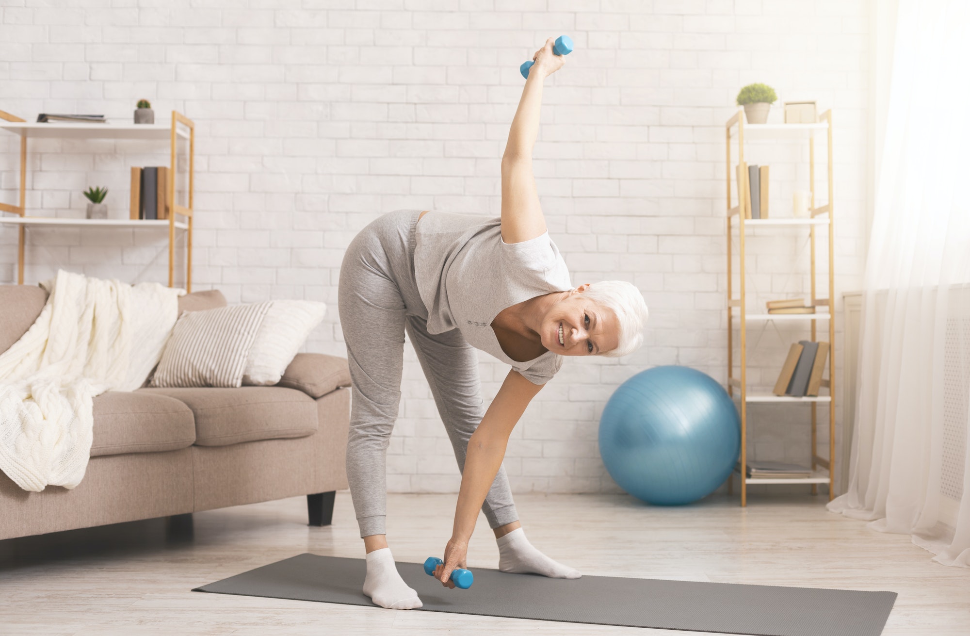 Senior lady exercising with dumbbells at home