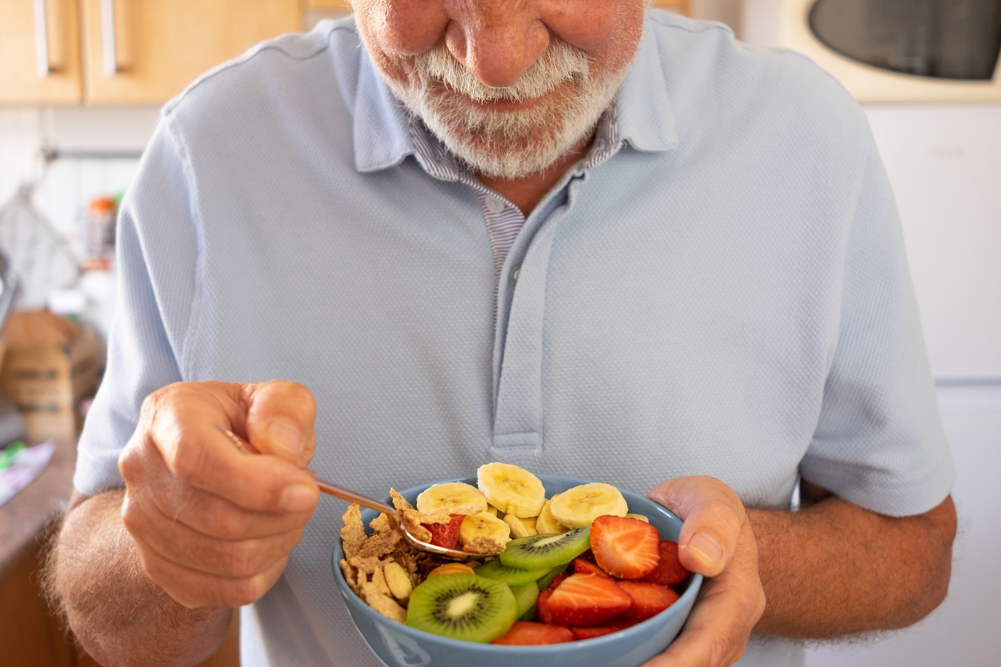 Senior man ready to eat a salad of fresh and dried fruits. Breakfast or lunch time, healthy eating