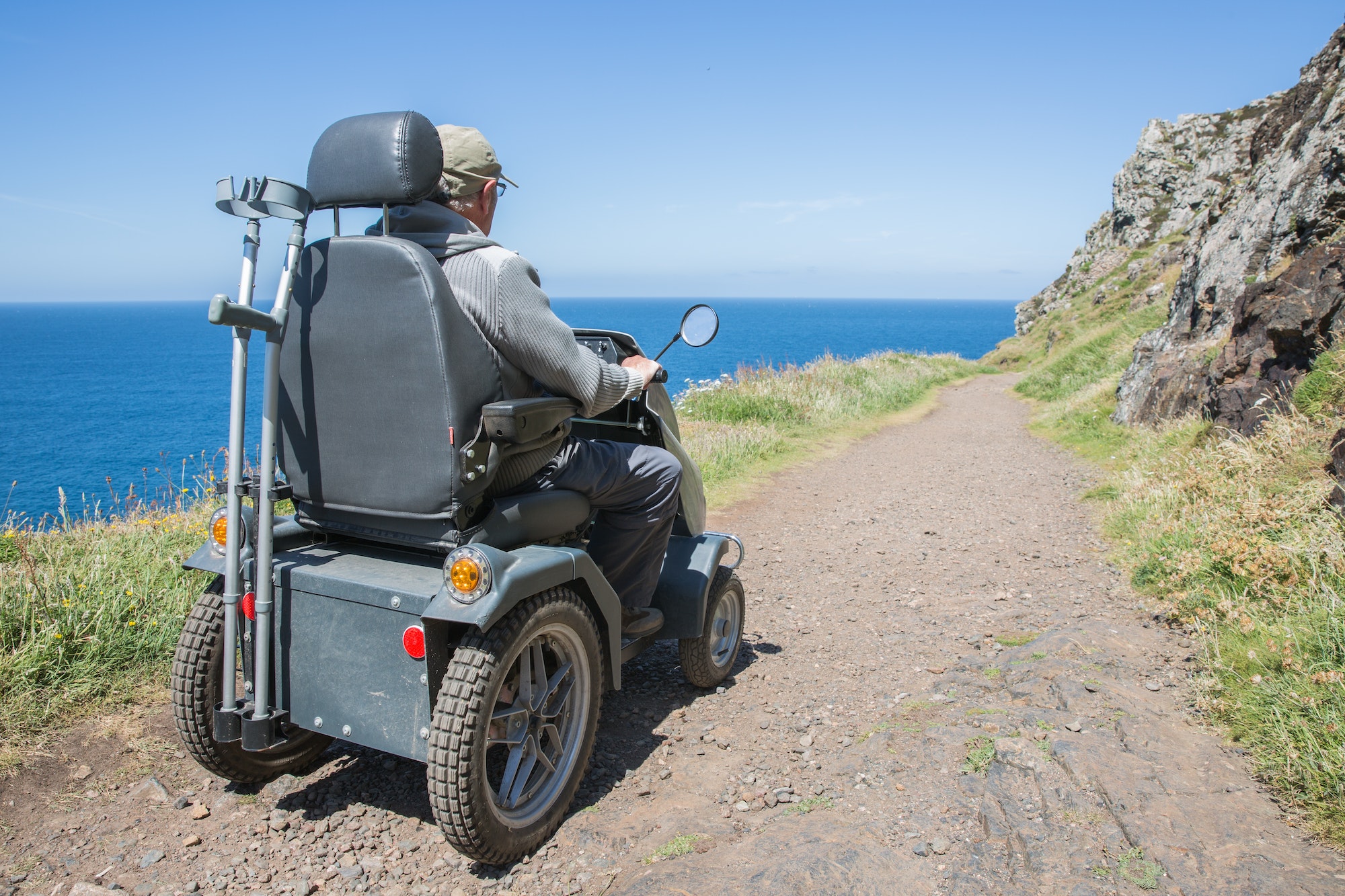 senior man riding a mobility scooter or tramper over rough terrain in an independence concept image