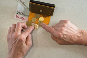 Senior person's hands count coins from wallet