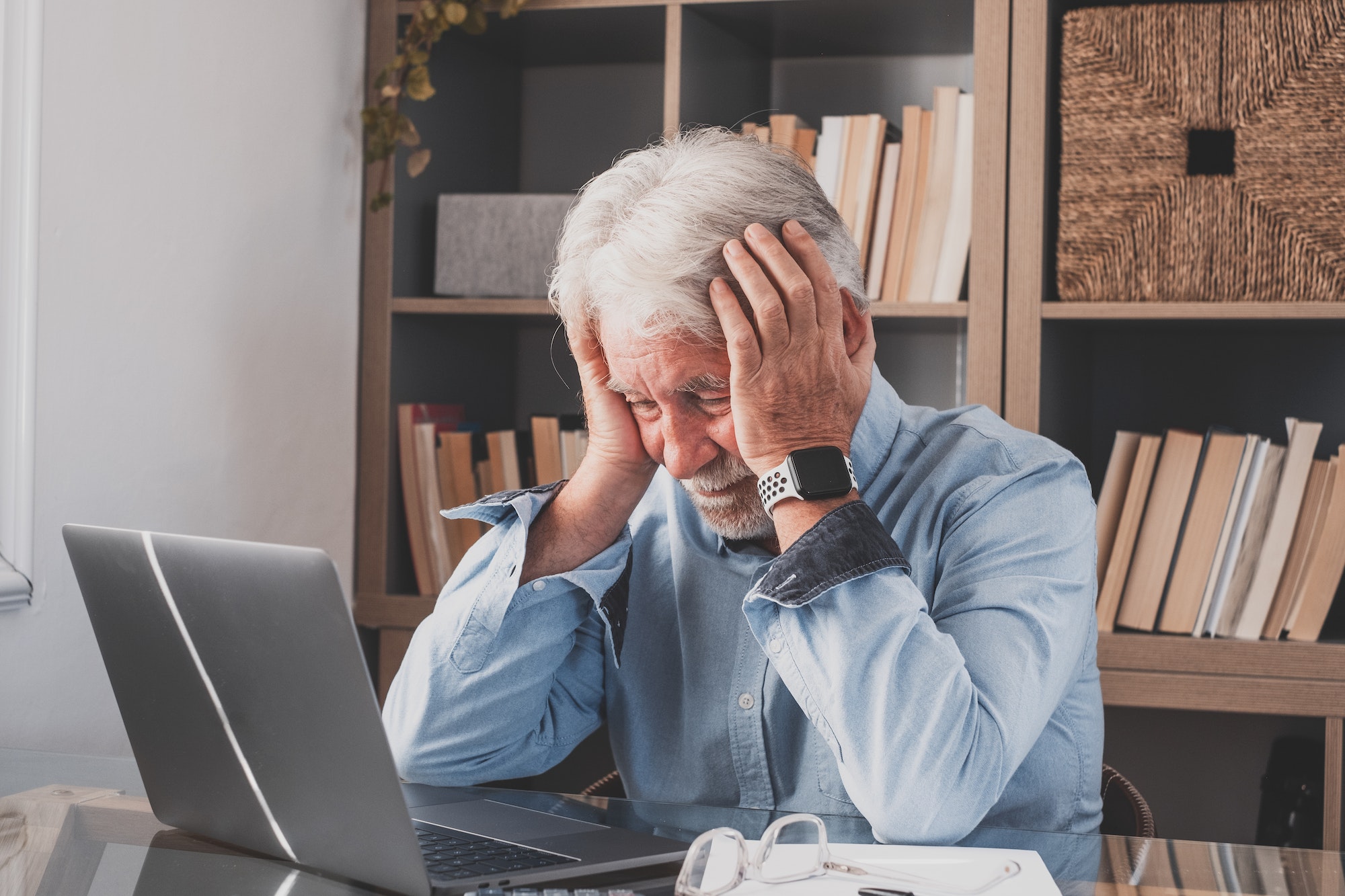 Unhealthy old stressed businessman looking at laptop, using computer, suffering from overwork